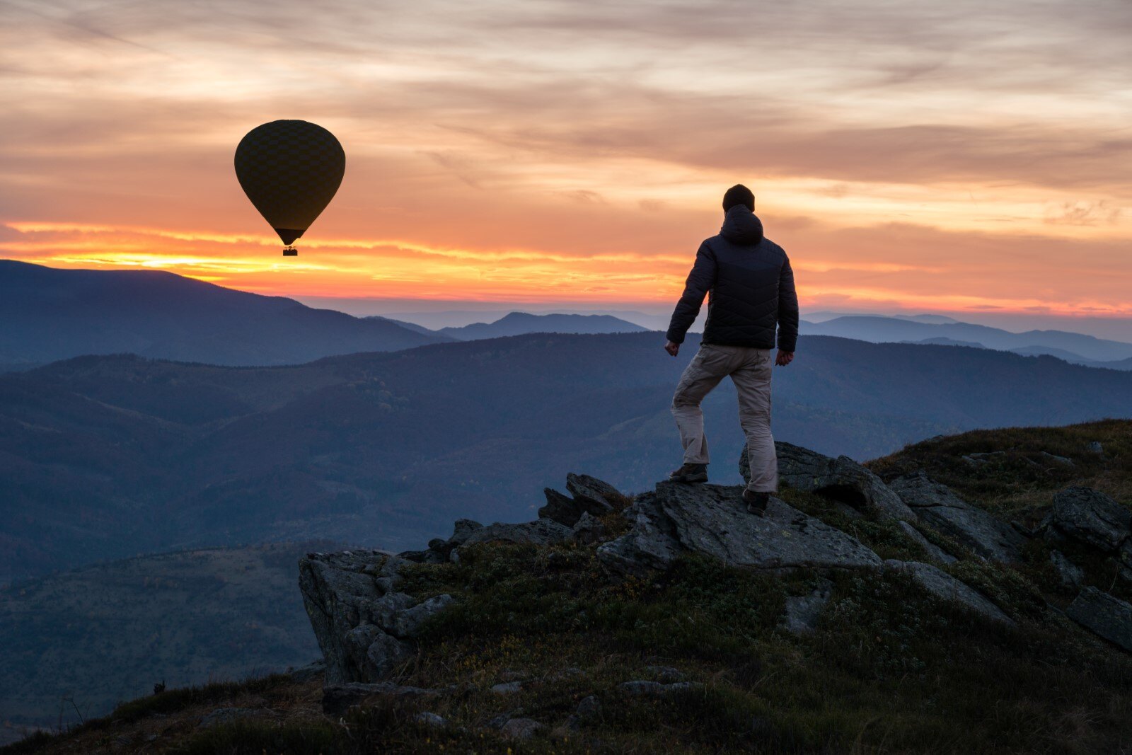 Header_Hiker-on-mountain-peak-with-air-balloon-at-sky-sunset-sundown-20231213-GLO-EN